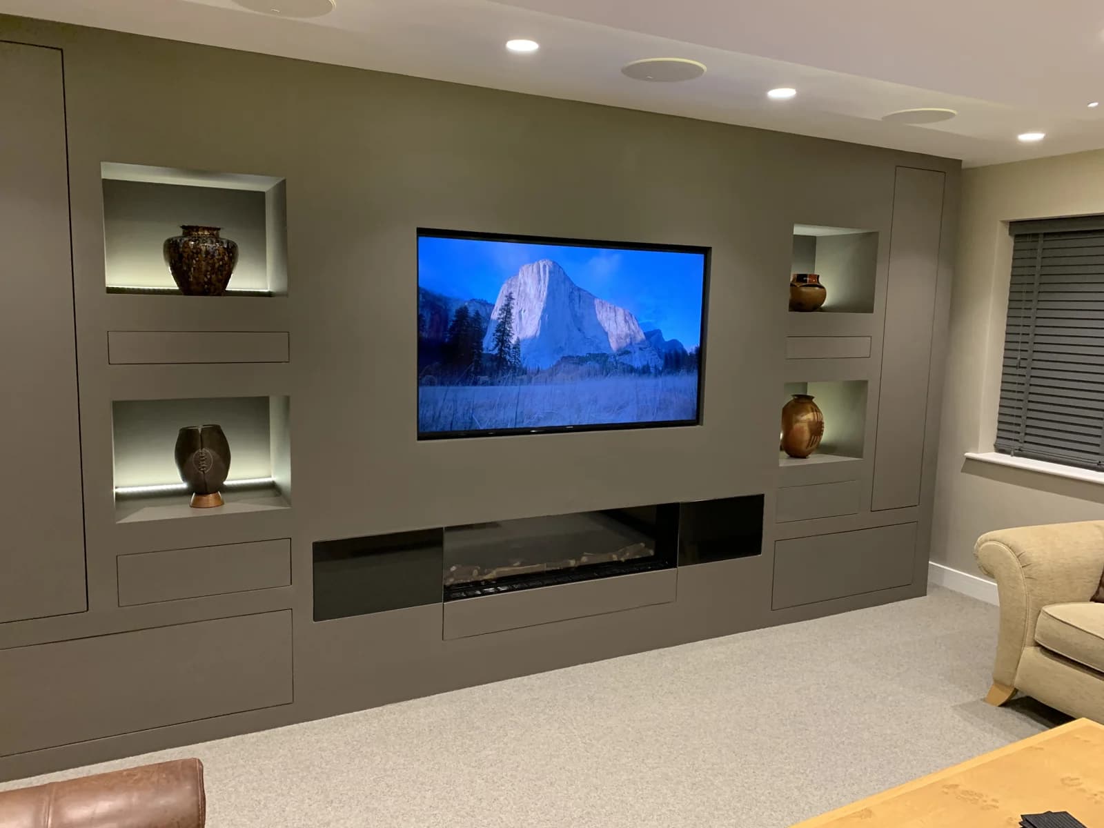 Built-in media wall with a TV, shelving and fitted cupboards