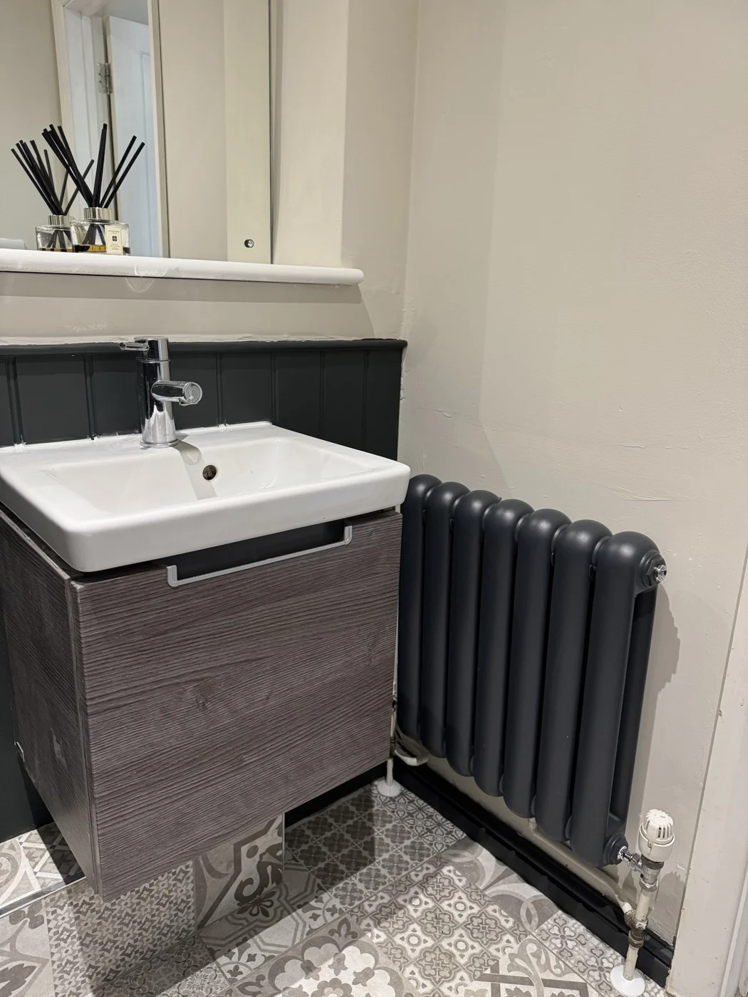 Finished basin area beside the dark radiator and painted panelling.