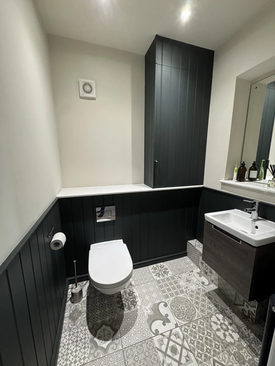 Updated bathroom with dark wall panelling and a new boiler cupboard.