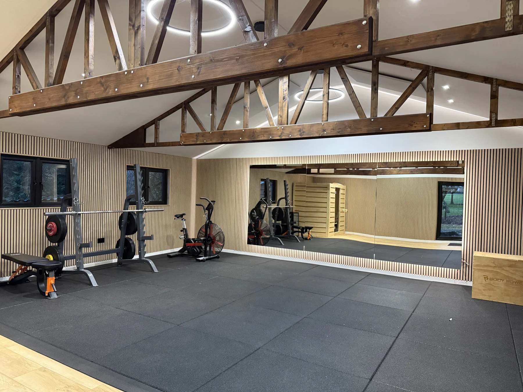 Finished gym with exposed beams, timber wall panels and a mirrored wall.